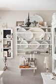 White decorative plates and platters in plate rack on pastel wall in rustic kitchen