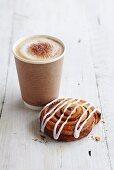 A coffee cup to take away with an iced Danish pastry