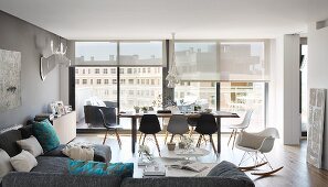 Blick von Sofalandschaft auf Essplatz mit Eames Chairs vor Fensterfront in großzügiger Penthouse-Wohnung