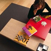 Frau beim Essen auf Bodentisch, rote Tischplatte auf Holzplatte