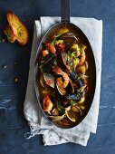 Bouillabaisse in a pan with garlic bread
