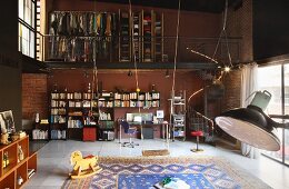 Zweigeschossiger Loftraum mit Bücher- und Schreibtischfront unter offener Kleidergalerie; mittig ein großer Teppich mit Schaukeln und Holzpferd