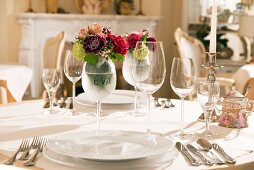 Festively set table with place settings, wine glasses and posy in wine glass labelled with name