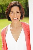 Dark-haired woman wearing top and cardigan in garden