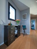 Industrial-style sideboard and metal chair in grey-painted hallway