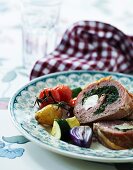 Meatloaf filled with spinach served with a side of vegetables