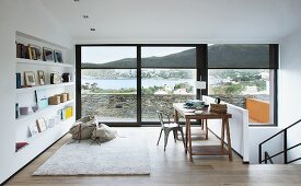 Vintage desk and chair and pictures on shelves fitted in niche in study with sea view