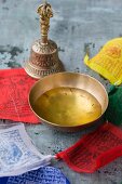 A bowl of saffron water, a Tibetian bell and prayer flags