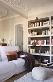 Seating area with bookcases, stucco ceiling, pouffe and white sofa