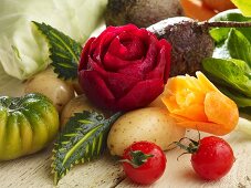 A carved beetroot rose, carrot flower and various types of vegetables
