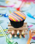 A cupcake decorated with coloured fondant stripes