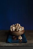 Mini meringues filled with coffee cream in a wooden bowl