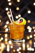 A Christmas cocktail with oranges, orange peel and a maraschino cherry