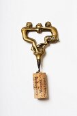 A brass corkscrew showing two men fighting over grapes, 1920- 1930s (Von Kunow Collection)