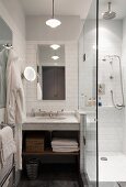 Marmorwaschtisch und Spiegel an weisser Fliesenwand, seitlich Glas-Duschabtennung in kleinen Badezimmer