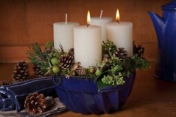Rustic Advent wreath with two lit candles in blue bundt cake tin