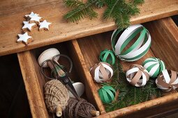 Hand-crafted baubles made from paper strips and bobbins of pale brown cord festively arranged with fir twigs and cinnamon stars