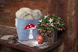 Balls of wool in hand-decorated felt basket with appliqué toadstool and Advent arrangement in rustic surroundings