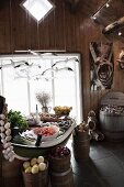 Gedeckter Esstisch und Holzbehälter mit Gemüse, oberhalb schwebende Möwen als Mobile in rustikalem Ambiente