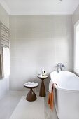 Zweiteiliges Beistelltischset aus Holz, neben freistehender weißer Badewanne am Fenster in modernem Bad mit Vintage Flair