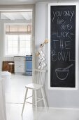 Beschriftete Tafel im weißen Vorraum und Blick in Küche mit Sprossenfenster und nostalgischem Flair