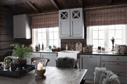 View across dining table of kitchen counter with grey-painted wooden doors in rustic wooden house
