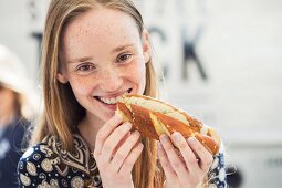 A smiling young woman with a white sausage hot dog