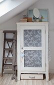Shabby-chic cupboard with lace fabric in panelled door