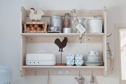 Pastel shabby-chic crockery and food stored in vintage-style jars and bottles on wall-mounted kitchen shelves