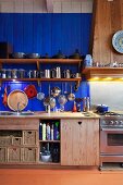 Kitchen counter with solid wooden base units below blue-painted wooden wall