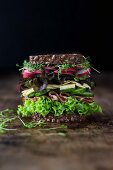 A large sandwich with lettuce, ham, cheese, cucumber, radishes and cress on wholemeal bread