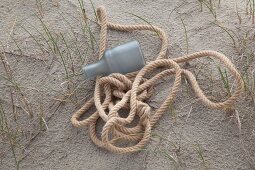 Rope and plastic bottle on sandy floor