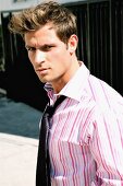 A young man wearing a pink and white striped shirt and black tie
