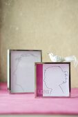 Hand-drawn silhouettes in chrome picture frames and bird ornament