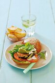 A burger with tomatoes, aubergines and avocado cream