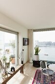 Rustic wooden bench in front of floor-to-ceiling terrace window and potted house plant in front of glass wall