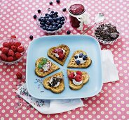 Herzwaffeln mit Beeren, Marmelade, Schokolade und Sahne