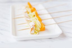 Spieße mit gerollten Zucchininudeln, Pfirsich und Käse auf Servierplatte