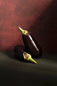 Two aubergines against a dark background