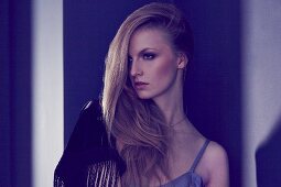 Portrait of a blonde woman wearing a vest top and a fringed shawl over her shoulder