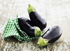 Three aubergines with a checked towel