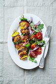 Spiced curry chicken and vegetable skewers with sesame seeds and tomato salad