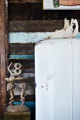 Afrikanische Holzskulptur neben Vintage Kühlschrank vor Holzbretterwand