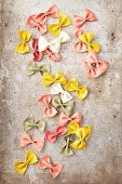 Various different coloured farfalle (natural, turmeric, spinach, beetroot) on a metal surface