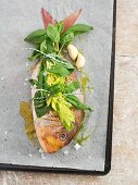 A raw bream with fresh herbs on a baking tray