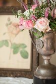 Bouquet of roses in antique silver trophy in front of botanical illustration