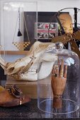 Wooden jointed hand wearing rings under glass dome in front of animal skin