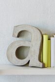 Deko-Buchstabe als Buchstütze aus Beton, neben gelb eingebundenen Büchern