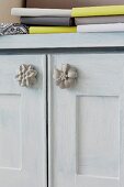 Concrete flower furniture knobs on doors of cabinet painted pale grey