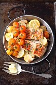 Oven-baked salmon trout with potatoes, lemons and cherry tomatoes